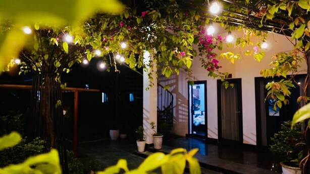 A covered outdoor area with a pergola, potted plants, and string lights. - Co To Center Homestay (Co To)