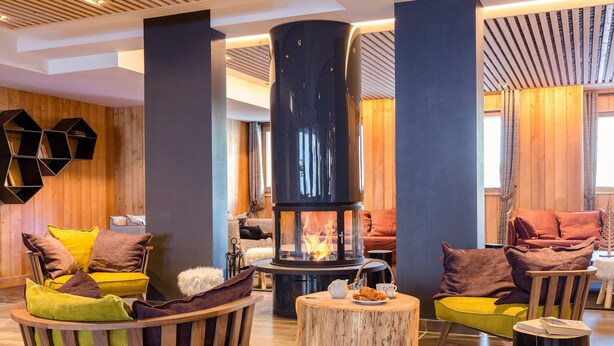 A cozy room with a central fireplace, wooden furniture, and a modern design.