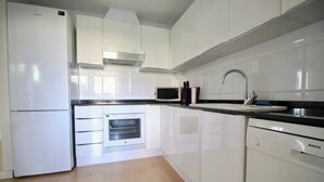 A modern kitchen with white cabinets, a microwave, a built-in oven, a Bosch dishwasher, and a stainless steel sink.