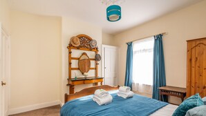 Una camera da letto con un letto, una cassettiera in legno, uno specchio e una finestra con tende.