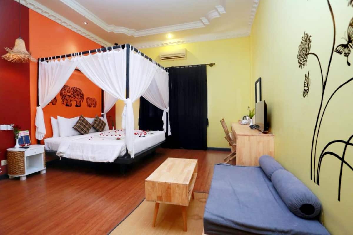 A room with a bed, a sofa, a wooden table, and a TV.