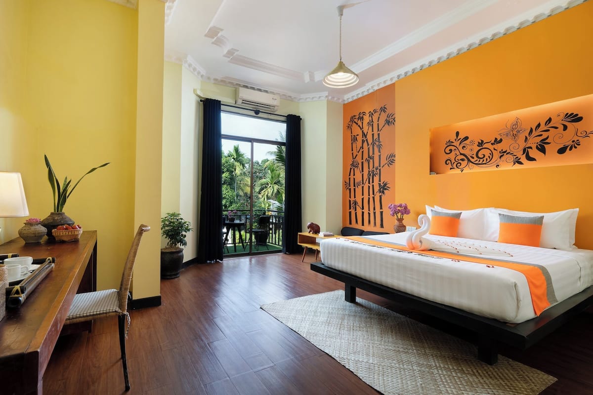 A hotel room with a bed, a desk, a chair, a window, and a balcony.