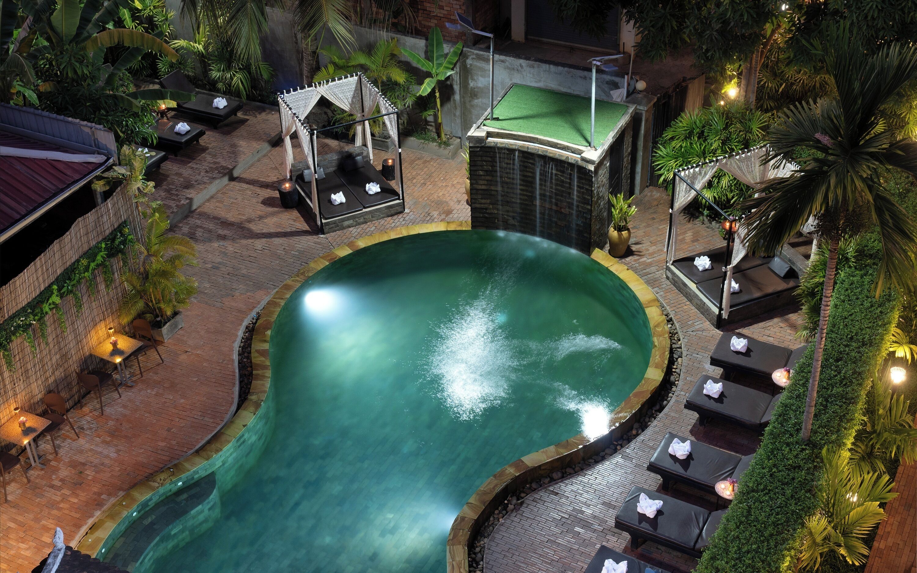 A pool area with lounge chairs and a small pavilion.