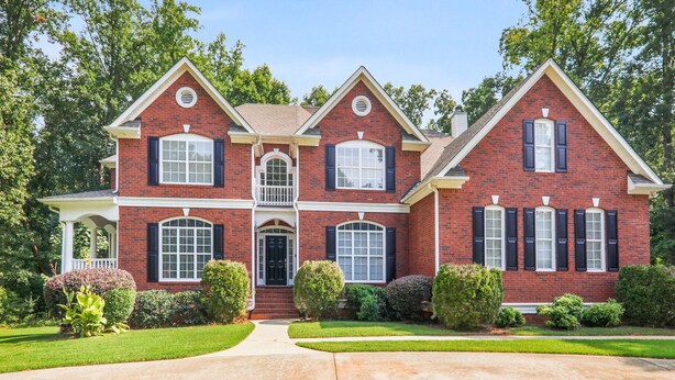 A two-story brick house with a front porch, multiple windows, and a well-maintained lawn. - Beautiful Atlanta Home Sleeps Up to 20 (Ellenwood)