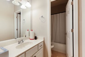 A bathroom with a white sink, mirror, and a shower curtain.