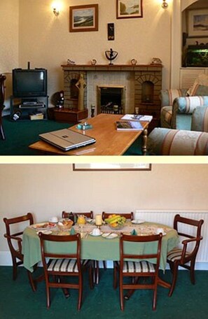 A living room with a fireplace, a television, and a dining area with a table set for four. - Ardgarry Holiday House (Inverness)