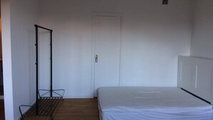 Une chambre avec un lit simple, une armoire en métal et une porte.