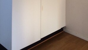 Une armoire blanche avec une tringle en métal et une poignée de porte.