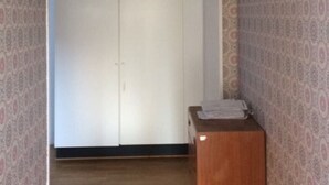 Un couloir avec un papier peint à motifs, un plancher en bois et une armoire blanche.