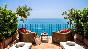 A terrace with wicker furniture, a table with a glass, and a view of the sea. - VILLA LUCE - Five Bedroom Villa, Sleeps 10 (Praiano)