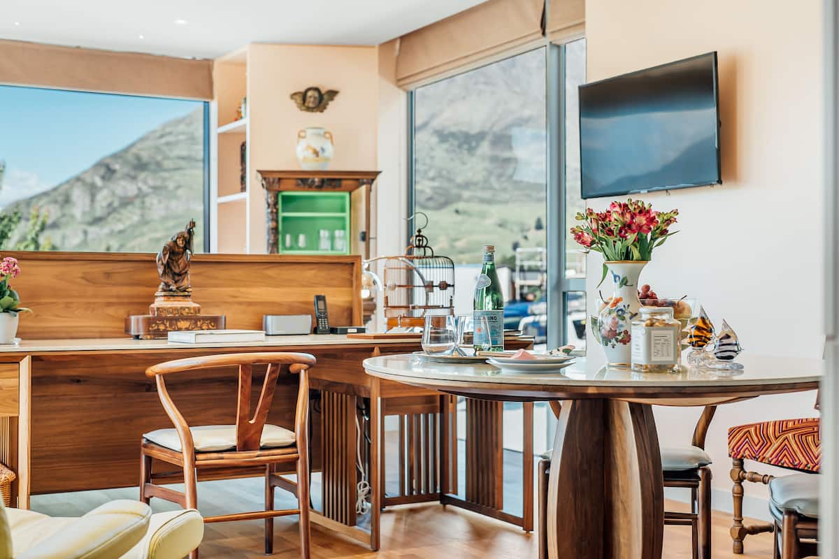 A modern kitchen with wooden cabinetry, a dining area with a round table, and a large window offering a mountain view.