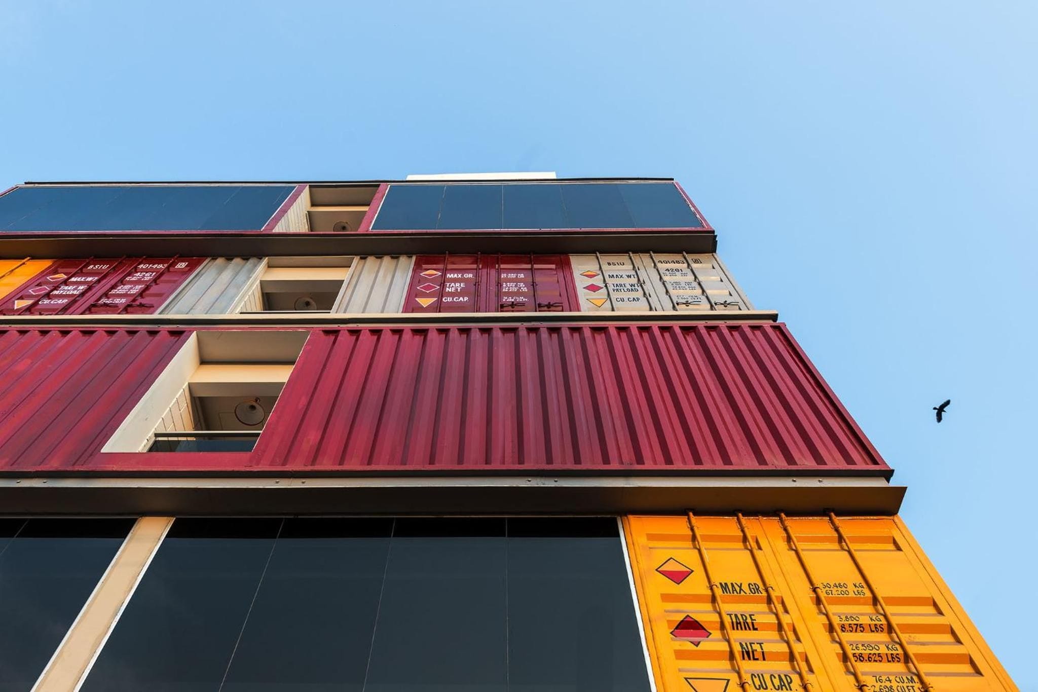A multi-story building with shipping containers used as walls, featuring weight capacity labels.