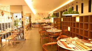 A restaurant with wooden tables and chairs, a bar area, and a wall with a decorative map. - The Port Hotel (Visakhapatnam)