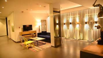 A modern living room with a sofa, a coffee table, and a TV. There is a striped rug on the floor.
