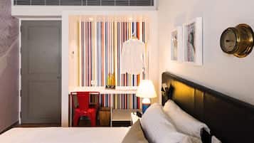Ein Hotelzimmer mit Bett, Schreibtisch mit Stuhl, Lampe und Wand mit Streifenmuster.