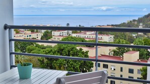A balcony with a view of buildings and the sea.