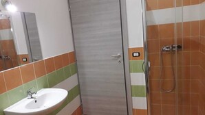 A bathroom with a sink, a door, and a shower area.