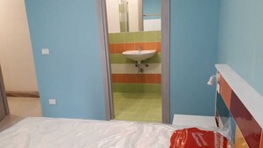 A hotel room with a bed, a bathroom with a sink, and a shower.