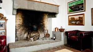 Une cheminée traditionnelle avec un foyer en briques, une cheminée en bois et une atmosphère rustique.