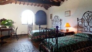 Une chambre avec deux lits, un plafond en bois, une fenêtre et un bureau avec une chaise.