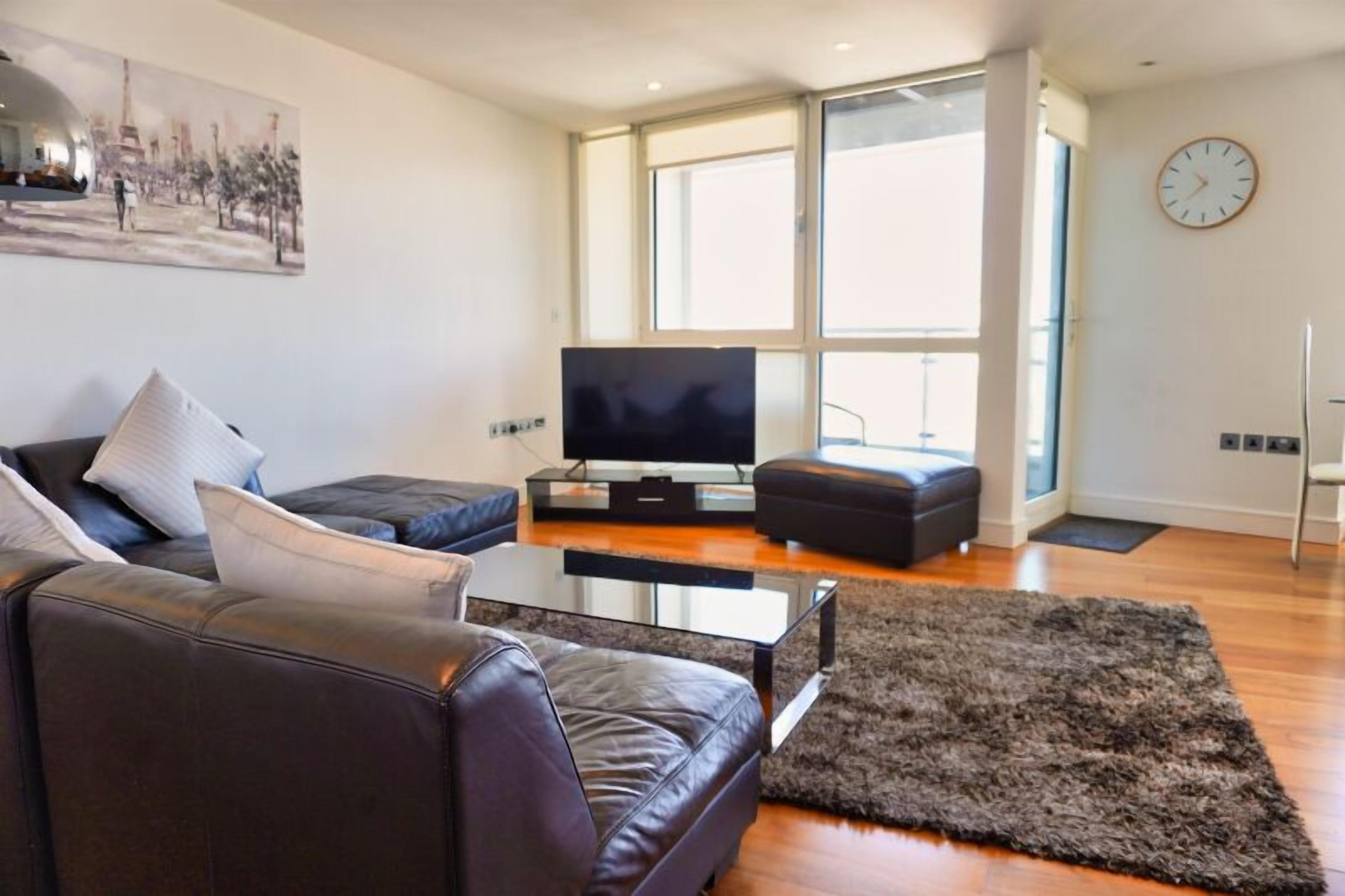 A modern living room with a leather sofa, a glass coffee table, and a flat-screen TV.