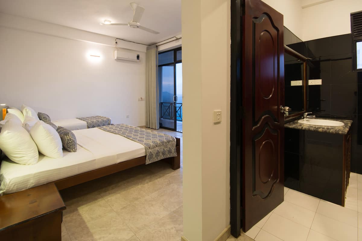 A bedroom with a bed, bedside table, and a view of the balcony. The bathroom features a sink and a mirror.