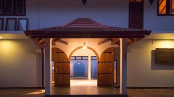 Entrada de hotel con un porche cubierto, puertas arqueadas y techo de tejas.