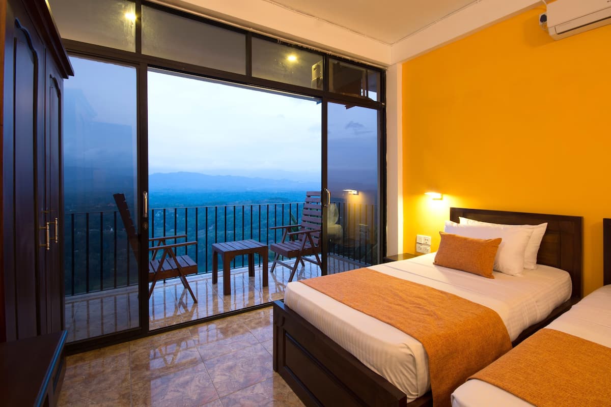 A hotel room with a balcony, a bed, a chair, and a view of the mountains.