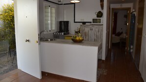 A compact kitchen with white cabinets, a built-in stove, and a small dining area. - Rent cozy apartment (Nivar)