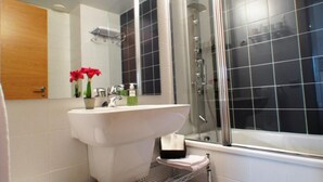 A modern bathroom with a white sink, a glass shower enclosure, and a wooden door. - Apartment in front of Fira Gran Via (Hospitalet de Llobregat - Barcelona)