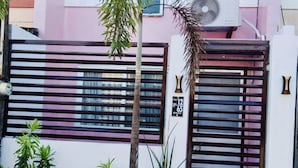 A residential area with a gated entrance, a palm tree, and potted plants. - ENTIRE HOUSE/ FULLY AIR CONDITIONED/ HiSpeed Wifi. Cable TV. Smart TV (Pampanga)