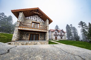 A stone building with a wooden balcony and a second-story balcony, surrounded by trees and a cobblestone path. - Foleya Mountain Resort (Tonya)