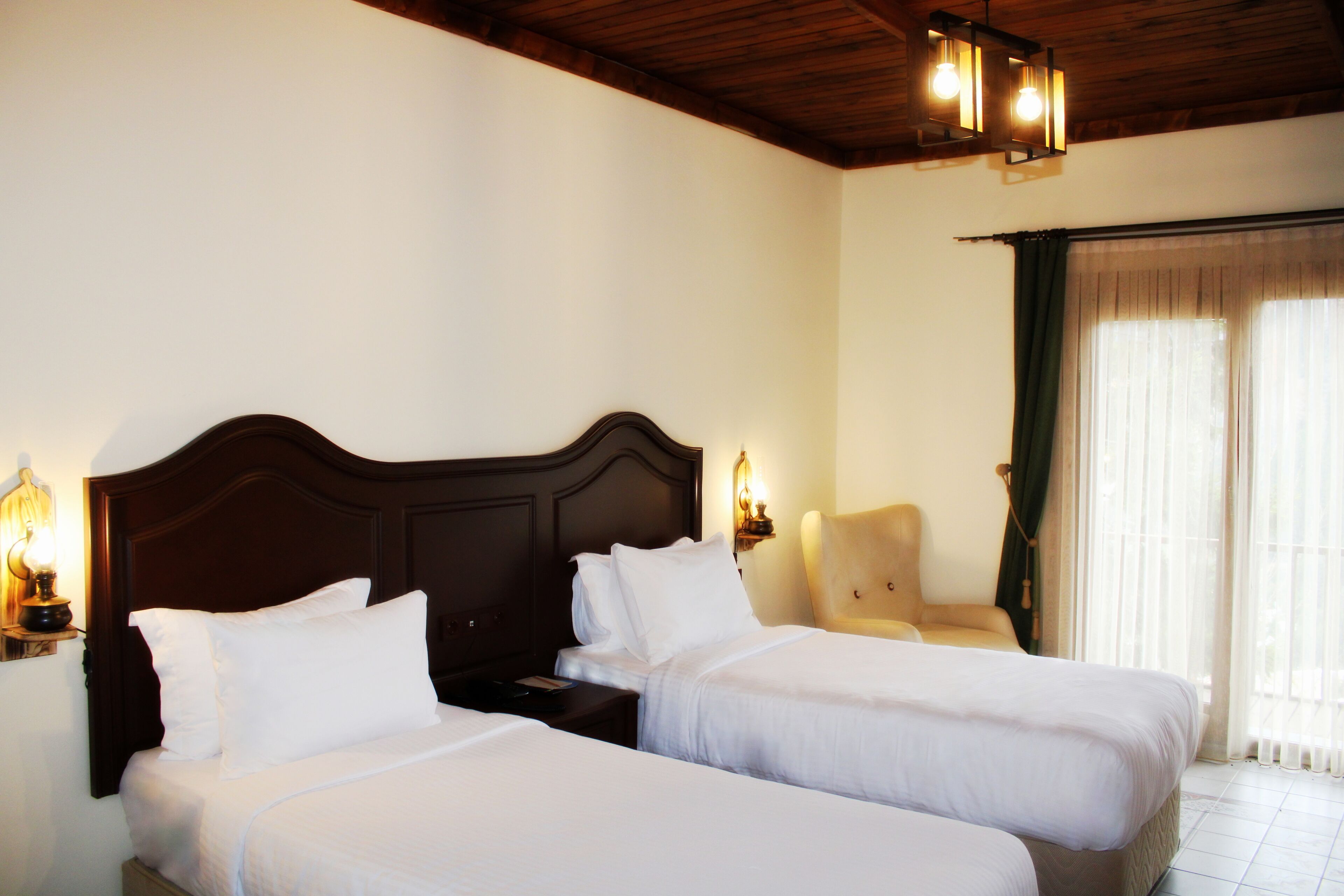 Una camera d'albergo con due letti, un soffitto in legno e una sedia.