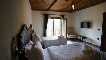 A hotel room with two beds, a TV, a chair, and a balcony with curtains.