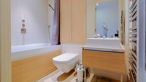 Et moderne badeværelse med badekar, toilet og vaskemøbel.