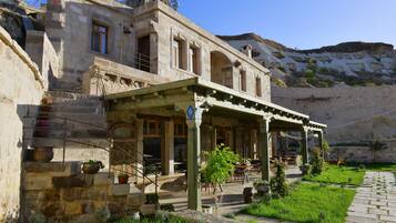 A stone building with a covered patio, outdoor seating, and potted plants.