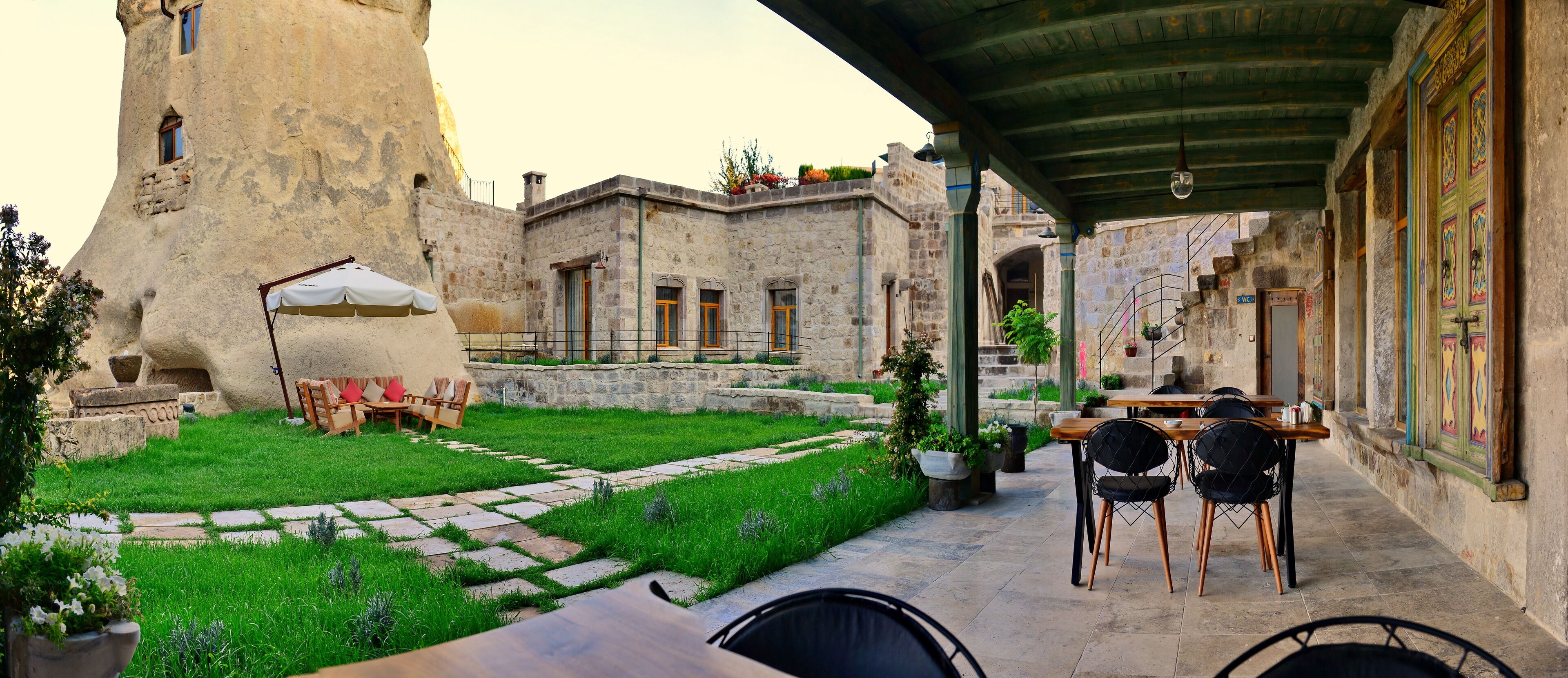 A courtyard with a stone building, outdoor seating, and a covered area.
