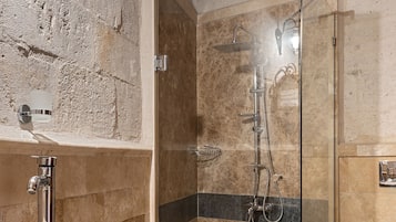 A bathroom with a stone sink, a glass-enclosed shower, and a white toilet.