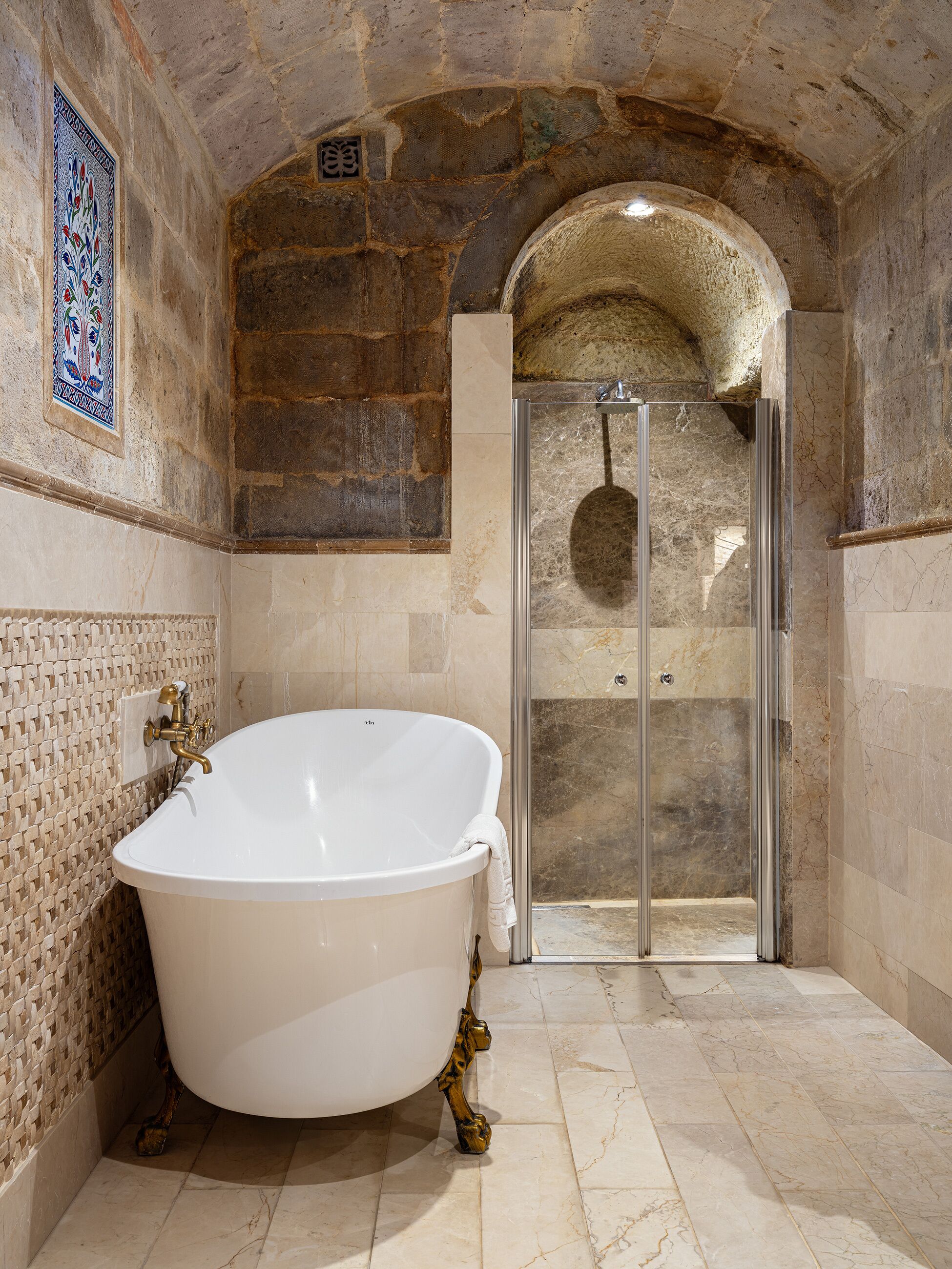 A bathroom with a freestanding bathtub, a glass-enclosed shower, and a mosaic tile wall.