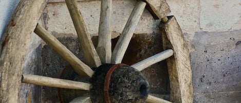 A white cat standing on a window sill next to a wooden wheel.