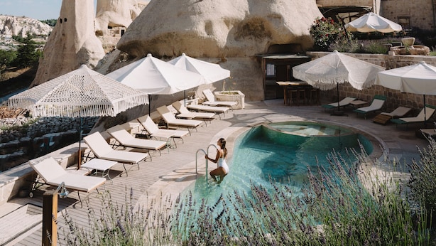 Um resort com piscina, espreguiçadeiras e uma formação rochosa peculiar.