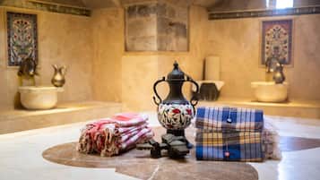 A room with a tiled floor, a decorative metal pitcher, a woven basket, and a folded plaid blanket.