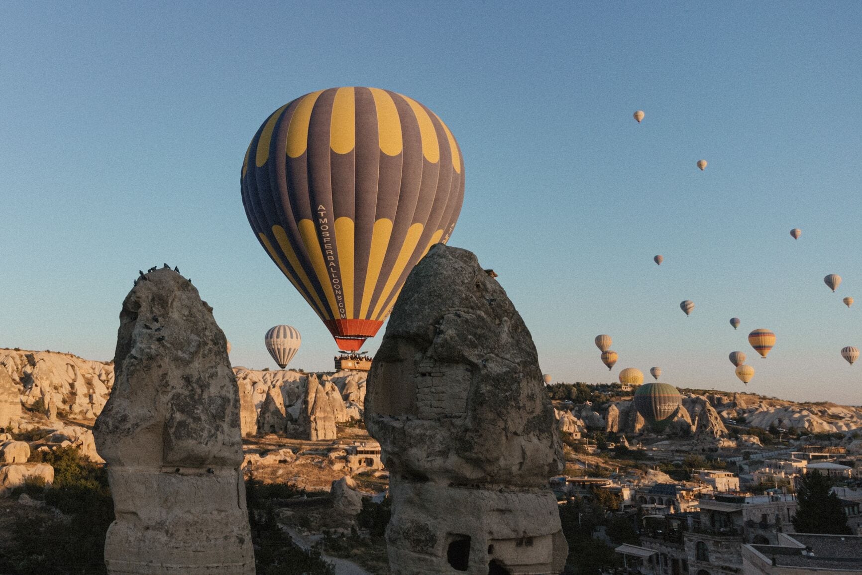 A hot air balloon over a rocky landscape with clear skies.