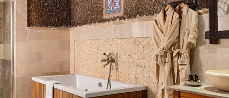 A bathroom with a freestanding bathtub, a wooden vanity, and a tiled floor.
