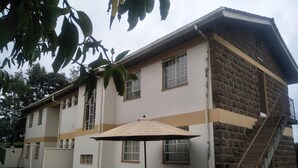 Un edificio de dos pisos con fachada de piedra, una escalera y un patio con una mesa y sillas.