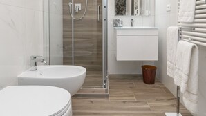 Een moderne badkamer met een douchecabine van glas, een wit wastafelmeubel en een toilet.