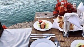 A table set for two with a view of the sea, a bottle of water, a glass, and a plate with food. - VILLA CHANI - Four Bedroom Villa, Sleeps 12 (Zanzibar)