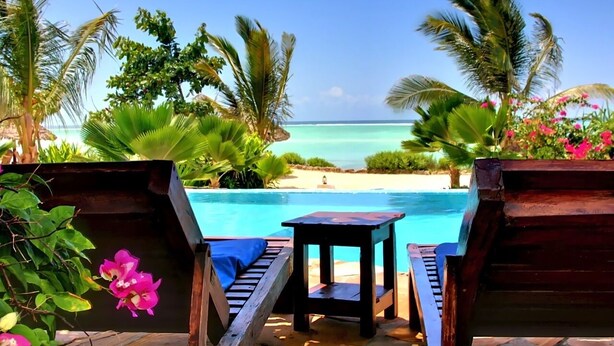 A wooden deck with a pool, surrounded by palm trees and tropical plants, overlooking a beach. - VILLA CHANI - Four Bedroom Villa, Sleeps 12 (Zanzibar)