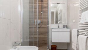 Een moderne badkamer met een douchecabine van glas, een witte wastafel en een ruime badkuip.