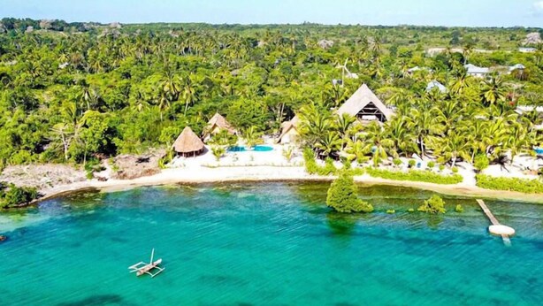 An aerial view of a tropical resort with overwater bungalows, clear turquoise water, and lush greenery. - VILLA FUKU - Four Bedroom Villa, Sleeps 10 (Zanzibar)